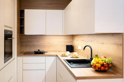 a kitchen with white cabinets and a bowl of fruit on the counter at Masarykova Residence - Modern 1-Bedroom in City Center & Free Parking in Ljubljana