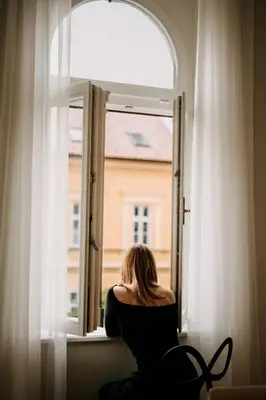 a woman sitting in a window looking out at Villa Elizabeth - Grand Family Apartment in Slovenj Gradec
