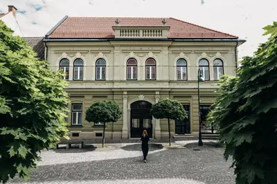 a woman walking in front of a building at Villa Elizabeth - Grand Family Apartment in Slovenj Gradec
