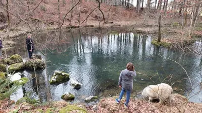two people standing next to a river with a sheep at Bobnarica in Grahovo