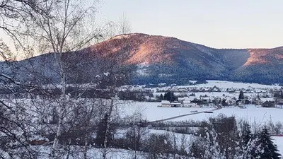 a snow covered hill with a town and a mountain at Bobnarica in Grahovo