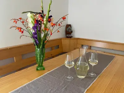 a table with three wine glasses and a vase with flowers at Vineyard Cottage Rigelj in Dolenjske Toplice
