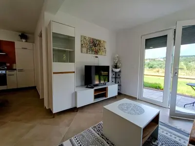 a white living room with a television and a table at Apartma LANA in Koper