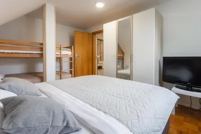 a bedroom with a bed and a tv and bunk beds at Apartments Leonid in Podčetrtek