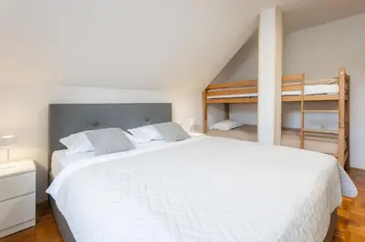 a bedroom with a large white bed and two bunk beds at Apartments Leonid in Podčetrtek