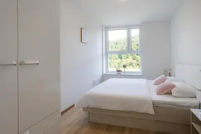 a white bedroom with a bed and a window at Apartment Dalgona Delux in Podčetrtek