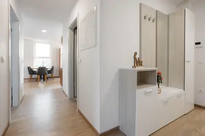 a hallway with white walls and a dining room with a table at Apartment Dalgona Delux in Podčetrtek