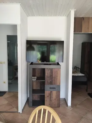 a flat screen tv on a stand in a living room at Bungalov in Gozd Martuljek