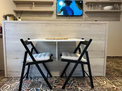a table with two chairs and a tv on a wall at CentralPark Suites in Maribor