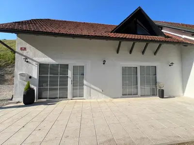 a white house with glass doors and a tile roof at CentralPark Suites in Maribor