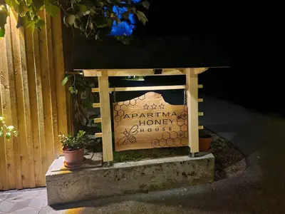a sign for a house with potted plants next to a fence at Honey house in Zgornje Gorje