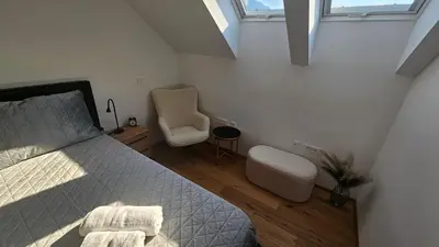 a bedroom with a bed and a chair and two windows at Apartment 1 Pearl in Bovec