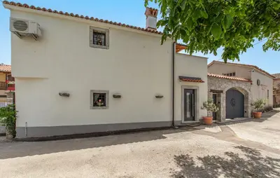 a white house with two windows and a door at Apartmaji Robida in Sežana
