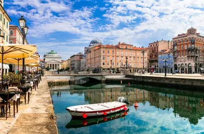 a boat in a river in a city with buildings at Apartmaji Robida in Sežana