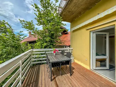 a wooden deck with a table on the side of a house at Apartmaji Vogelnik in Radovljica