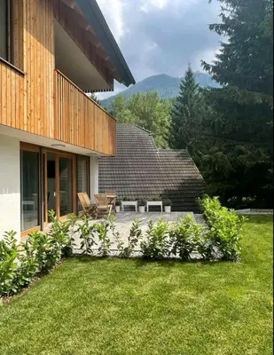 a patio of a house with a grass yard at Apartma Gorna in Kranjska Gora