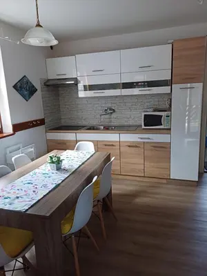 a kitchen with a wooden table and white cabinets at Hišica 6084 Terme Čatež in Mostec