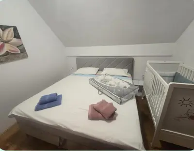 a bed with a crib with two towels on it at Hišica 6084 Terme Čatež in Mostec