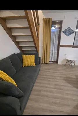 a living room with a couch and a staircase at Hišica 6084 Terme Čatež in Mostec
