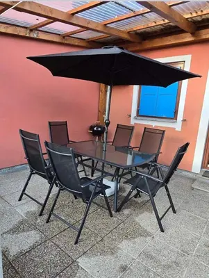 a black table with chairs and an umbrella at Hišica 6084 Terme Čatež in Mostec