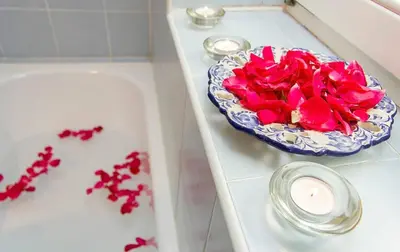 a table with a bowl of red flowers and a candle at VILA BREDA in Bled center in Bled
