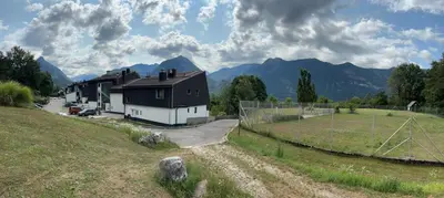 a house in a field with mountains in the background at Apartma Tine in Bovec