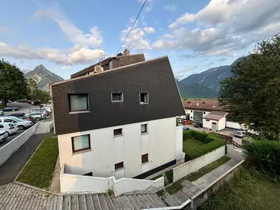 a white building with a black roof on a street at Apartma Tine in Bovec