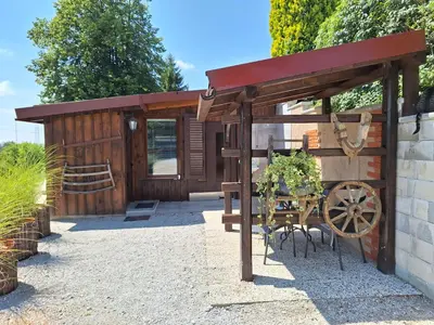 a wooden shed with a table and a wooden wheel at Štibelc FRIDA in Izlake