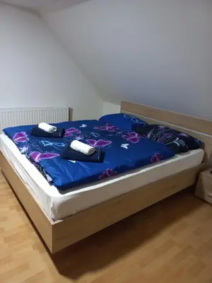 a bed with a blue comforter and two towels at FAMILY HOUSE Pri Kovaču in Soča