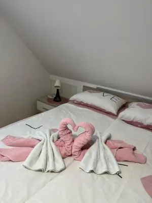 a bed with pink towels and two flamingos forming a heart at FAMILY HOUSE Pri Kovaču in Soča