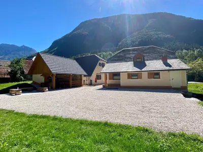 a house with a gravel driveway in front of a mountain at FAMILY HOUSE Pri Kovaču in Soča