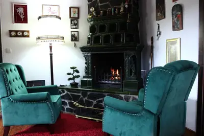 a living room with two chairs and a fireplace at Na Gmajni pr' Angležu in Gabrovka