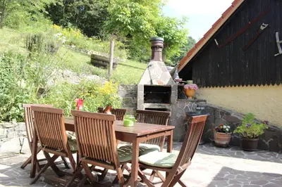 a patio with a table and chairs and an outdoor oven at Na Gmajni pr' Angležu in Gabrovka