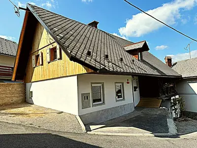 a house with a gambrel roof on a street at Apartma Pr'Komarjo in Zgornje Gorje