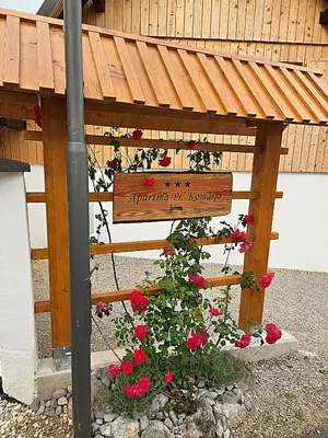 a sign in front of a building with red roses at Apartma Pr'Komarjo in Zgornje Gorje