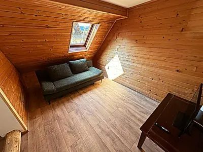 an attic room with a couch in a wooden room at Apartma Pr'Komarjo in Zgornje Gorje