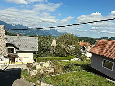 a view of a house with mountains in the background at Apartma Pr'Komarjo in Zgornje Gorje