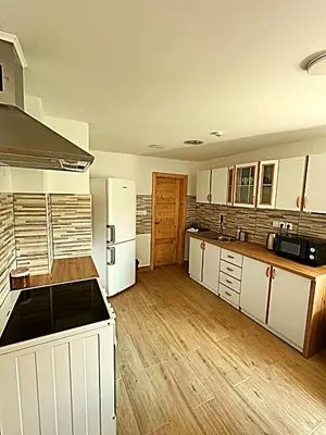a large kitchen with white appliances and wooden floors at Apartma Pr'Komarjo in Zgornje Gorje