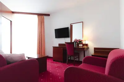 a hotel room with red chairs and a desk and a television at Hotel Čatež - Terme Čatež in Čatež ob Savi