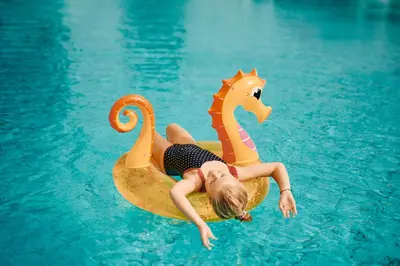 a girl is laying on a plastic swan in a pool at Hotel Čatež - Terme Čatež in Čatež ob Savi