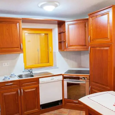 a kitchen with wooden cabinets and a white dishwasher at Holiday Home Zelenka in Cerklje na Gorenjskem