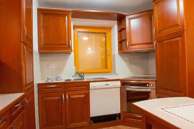 a kitchen with wooden cabinets and a white dishwasher at Holiday Home Zelenka in Cerklje na Gorenjskem