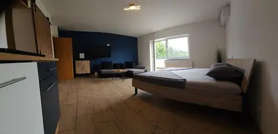 a bedroom with a bed and a kitchen with a desk at Grmač Apartments in Naklo