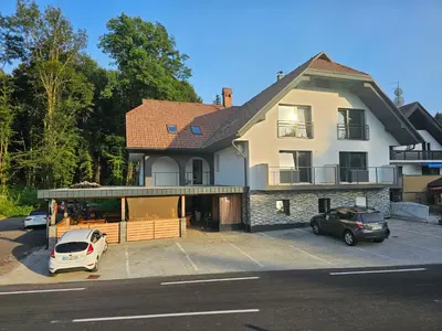 a large house with cars parked in a parking lot at Grmač Apartments in Naklo