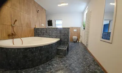 a large bathroom with a tub and a toilet at Grmač Apartments in Naklo