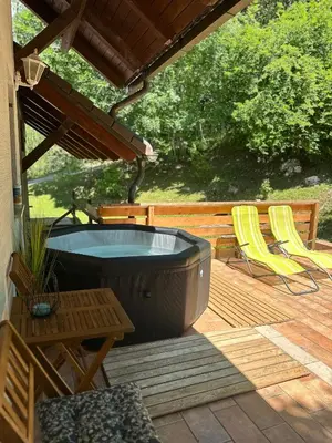 a hot tub on a deck with a table and chairs at green breeze - private jacuzzi retreat in Žalec