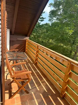 a wooden porch with a chair and a table at green breeze - private jacuzzi retreat in Žalec