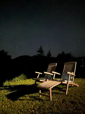 two wooden chairs sitting in a field at night at Glamping Na Vrhu in Višnja Gora
