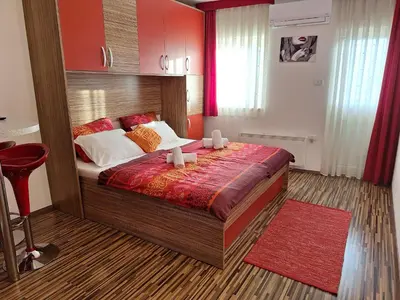 a bedroom with a large bed and a red rug at Apartmaji Paradiso in Komen