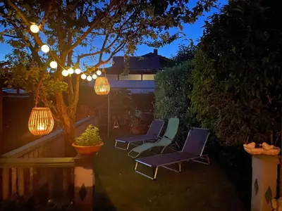 a patio with purple chairs and lights and a tree at Green Garden Home in Cerknica